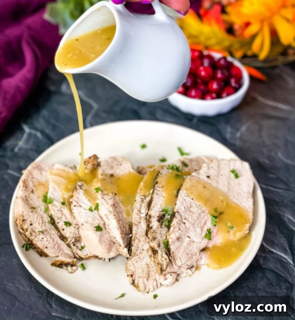 Instant Pot Tender Turkey Breast 11 Cooked turkey breasts with homemade gravy on a white serving plate, accompanied by autumn decorations.