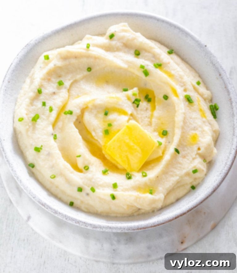 Creamy Keto Cauliflower Mashed Potatoes in a bowl, garnished with fresh herbs