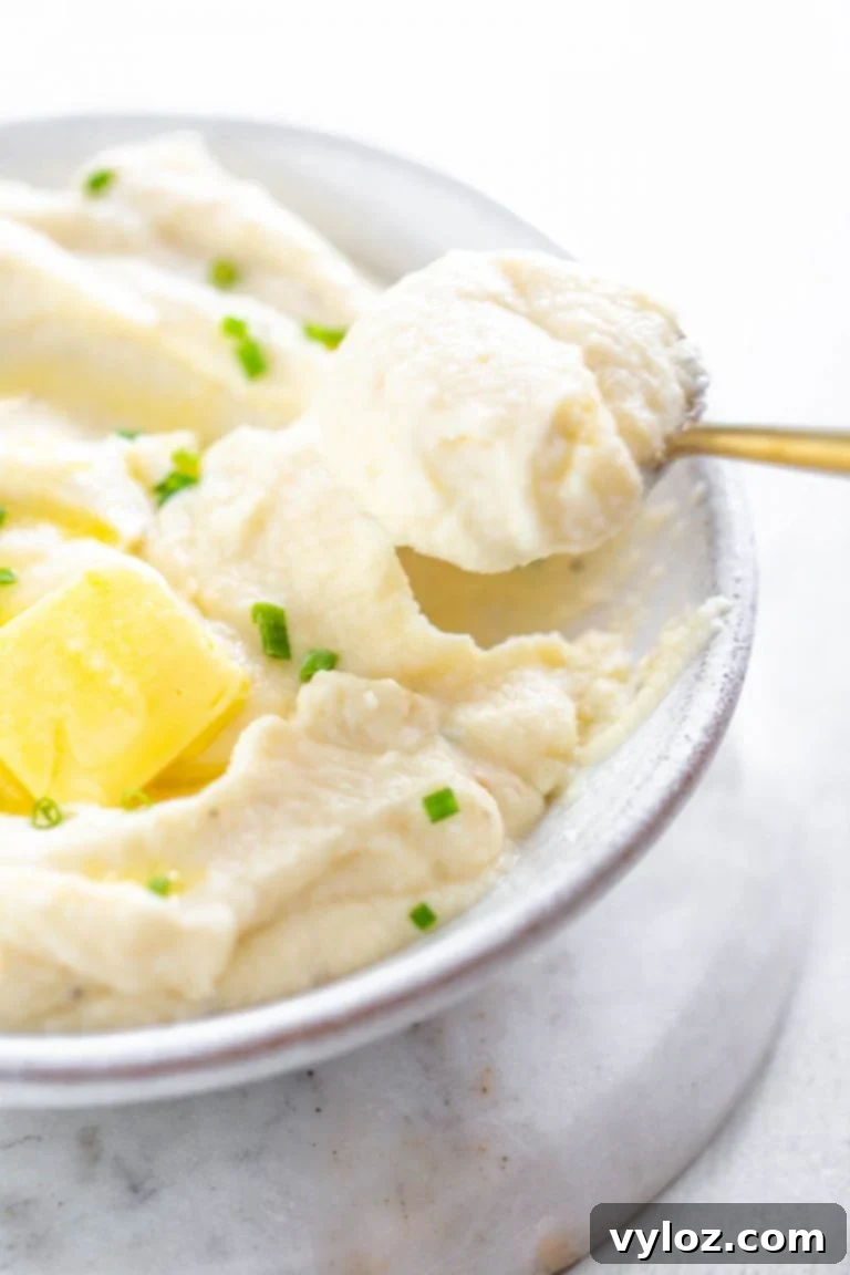 A spoonful of creamy keto cauliflower mashed potatoes with a hint of green garnish