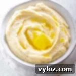 Keto cauliflower mashed potatoes in a glass bowl, garnished with herbs