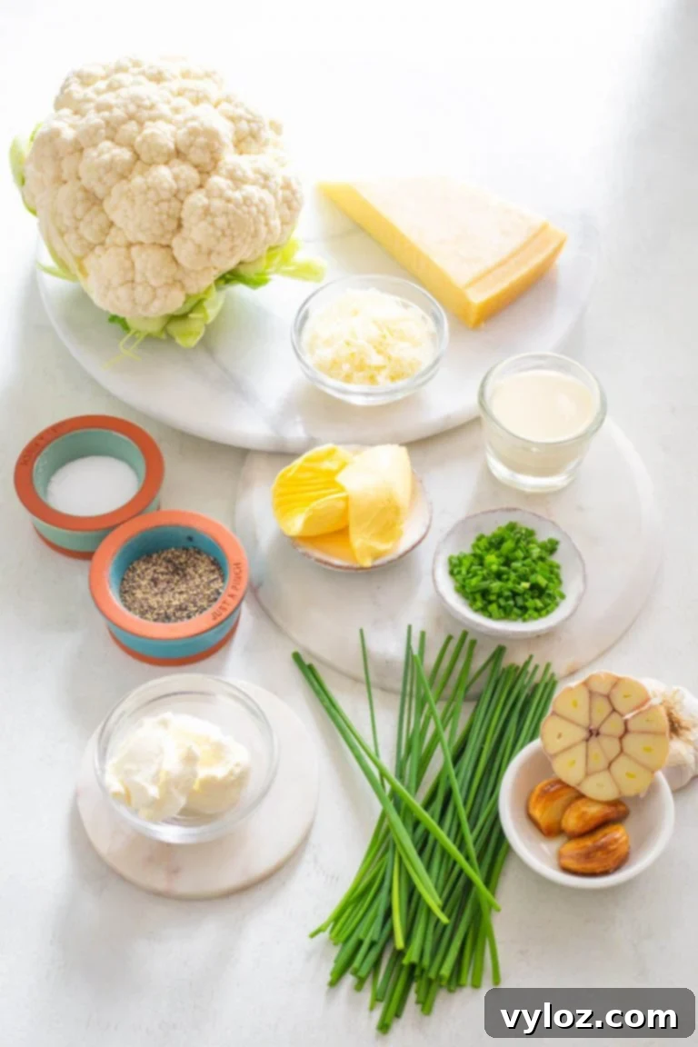 Ingredients laid out for Keto Cauliflower Mashed Potatoes: cauliflower, cream cheese, butter, garlic, heavy cream, parmesan, salt, pepper