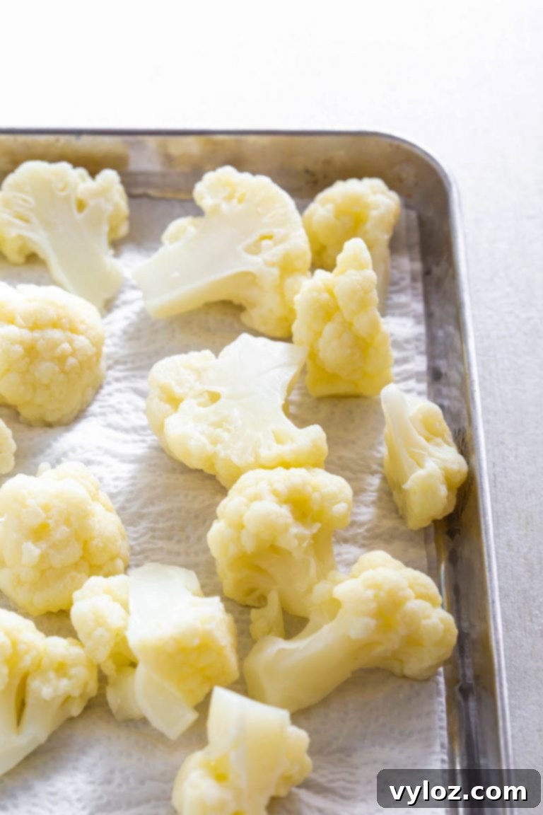 Fresh raw cauliflower head on a cutting board, ready for preparation