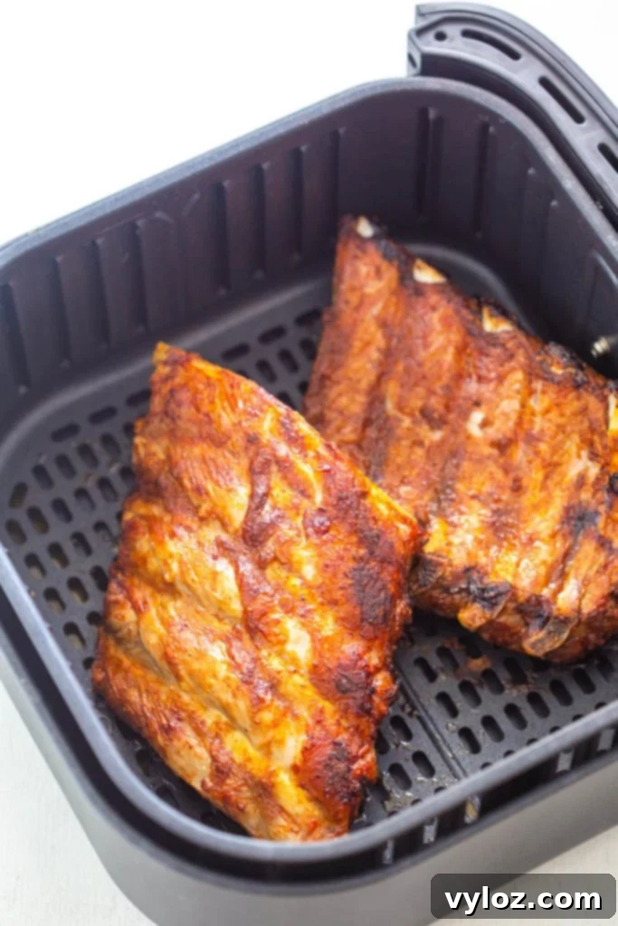 A rack of seasoned ribs cooking inside an air fryer basket