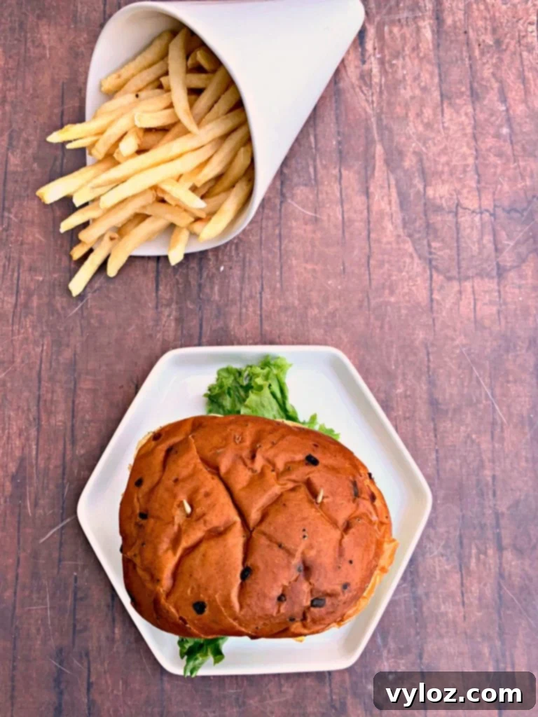 juicy air fryer cheeseburgers on a bun and white plate with fries