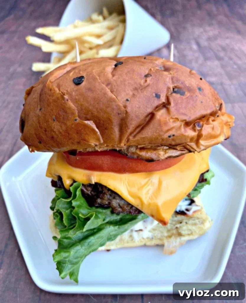 juicy air fryer cheeseburgers on a bun and white plate with fries