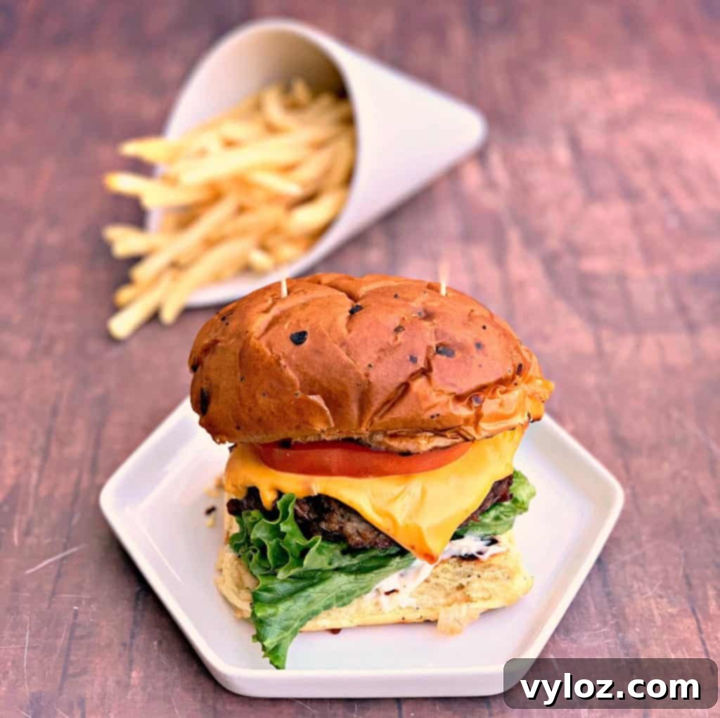 juicy air fryer cheeseburgers on a bun and white plate with fries