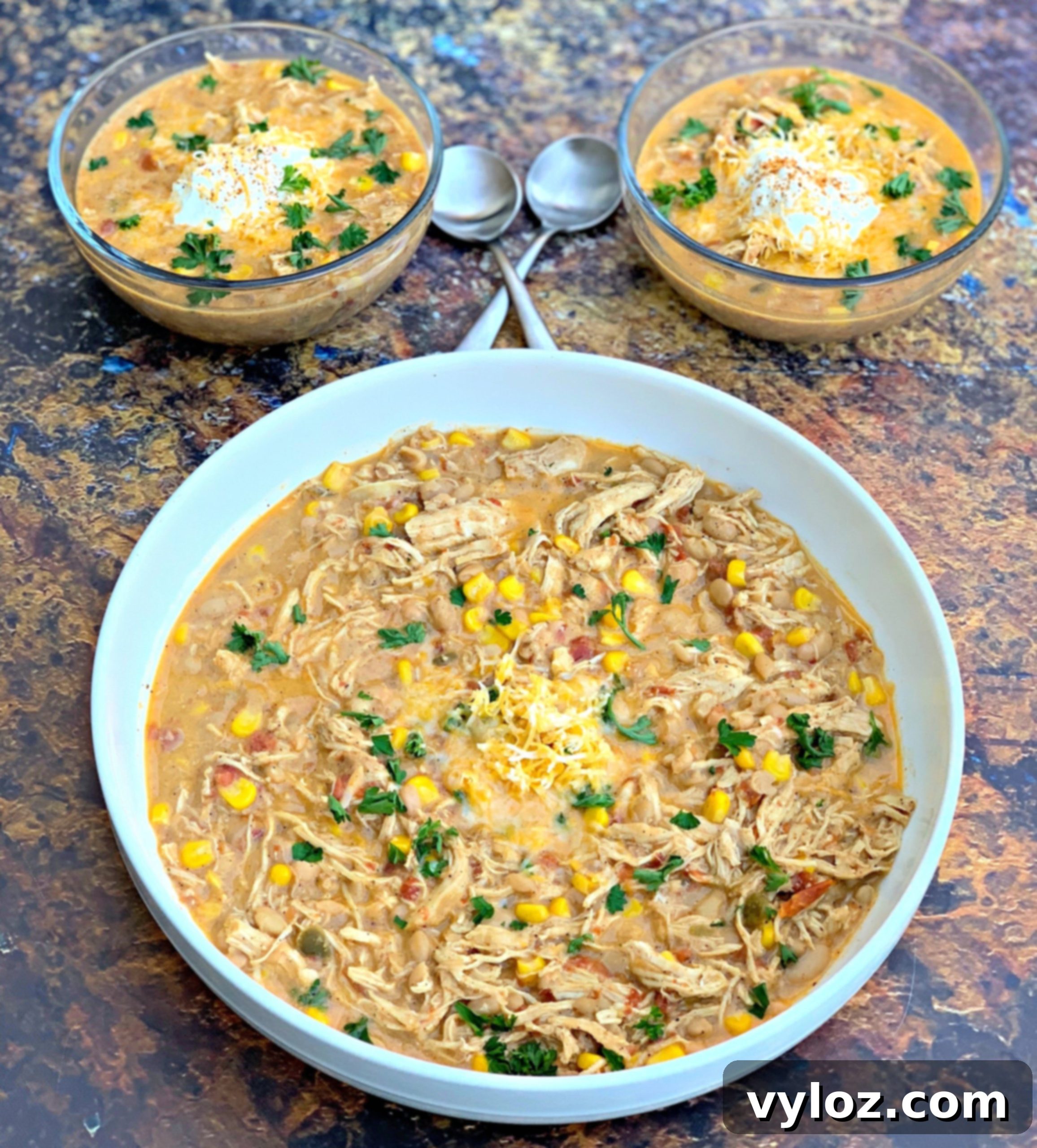 Overhead shot of white chicken chili ingredients laid out on a rustic wooden table, including chicken, beans, spices, and vegetables.