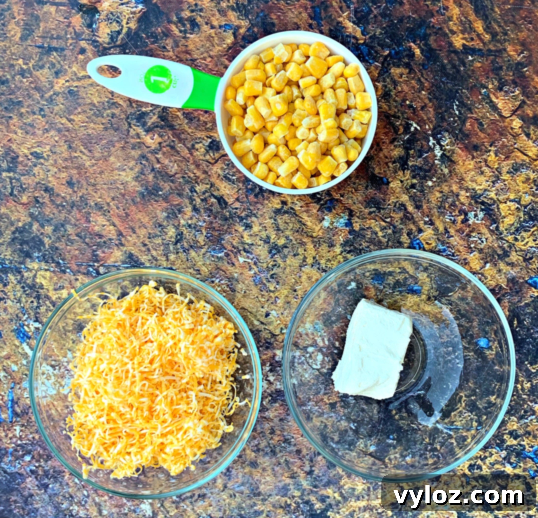 Bowls filled with cream cheese, shredded cheese, and frozen corn kernels, ready to be added to the chili.