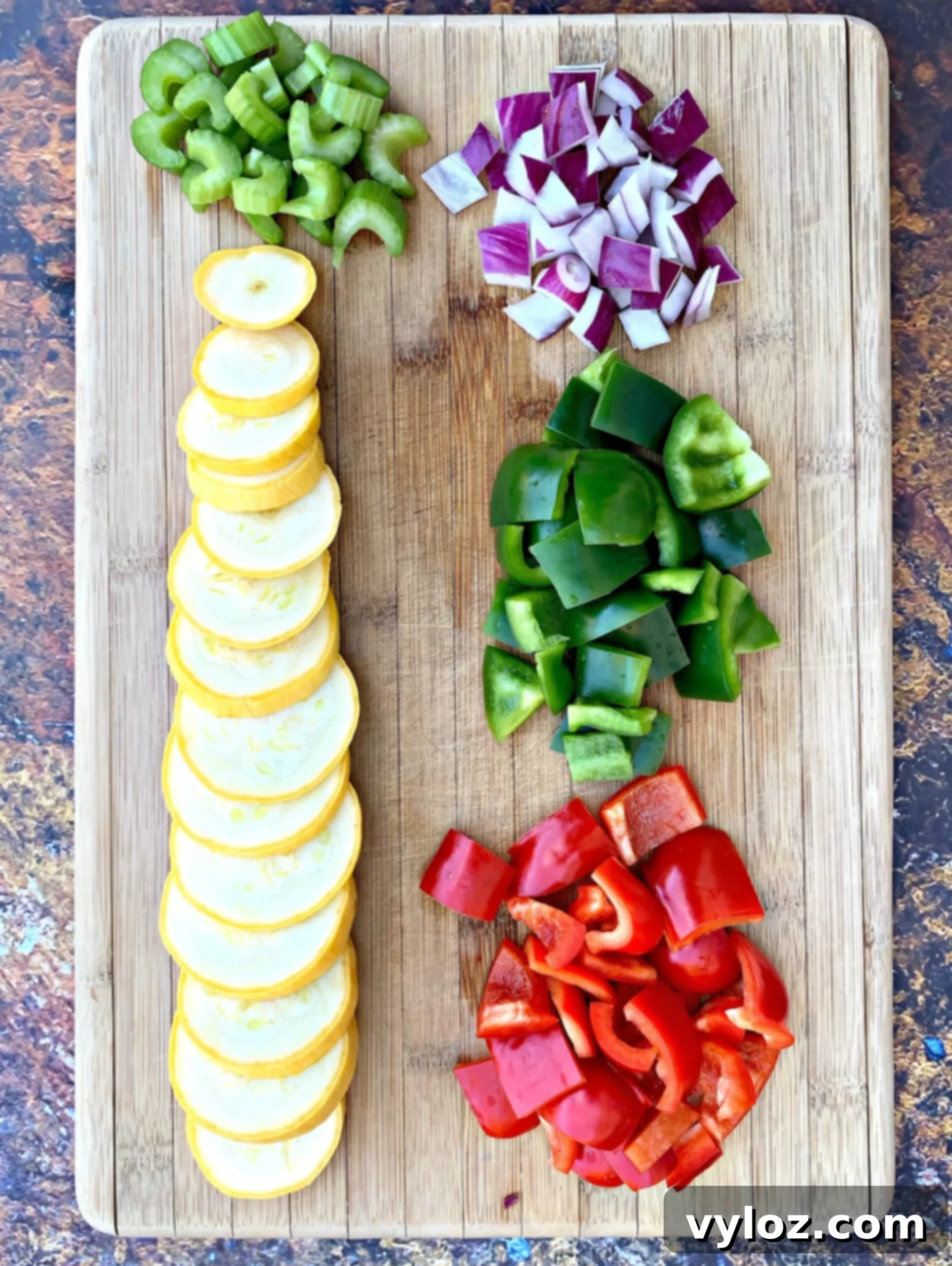 Hearty Cajun Chicken and Sausage Skillet 3 Freshly chopped vegetables, including bell peppers, onions, and celery, on a cutting board