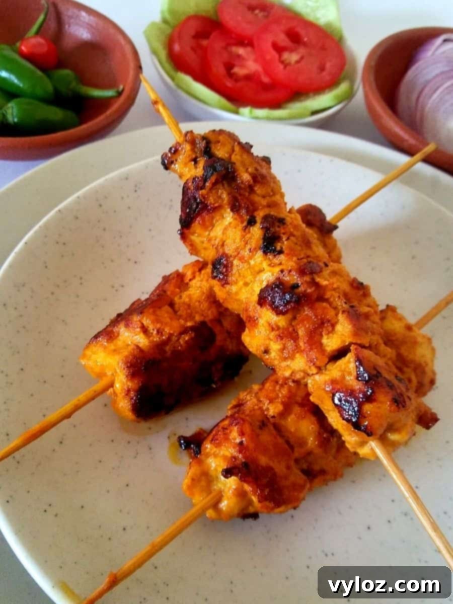 Image showing chicken boti Kabab on skewer sticks, garnished with lemon and onion slices.