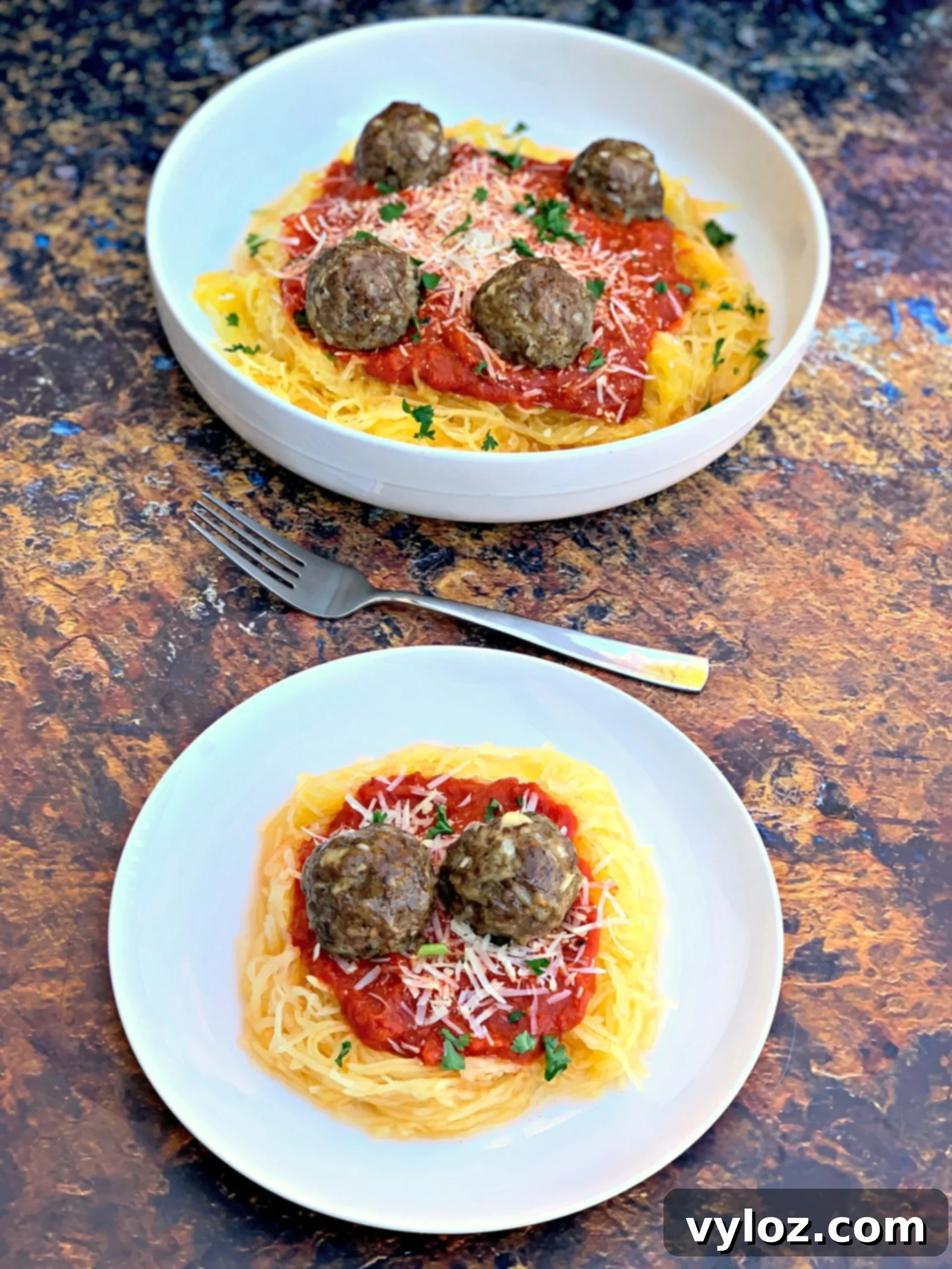 A hearty serving of spaghetti squash marinara with meatballs, elegantly presented in a white bowl, placed on a minimalist white plate for a clean and inviting aesthetic.