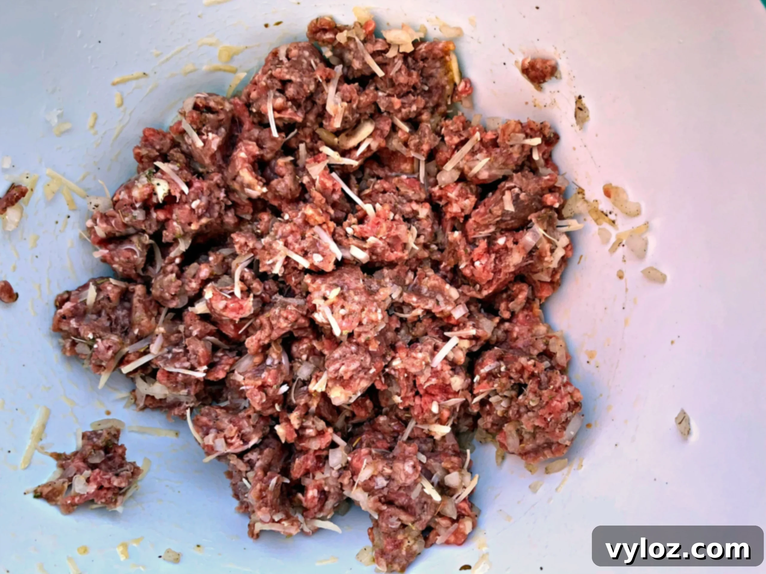 A close-up shot of seasoned raw ground beef in a bowl, meticulously prepared and ready for forming into perfectly shaped meatballs.