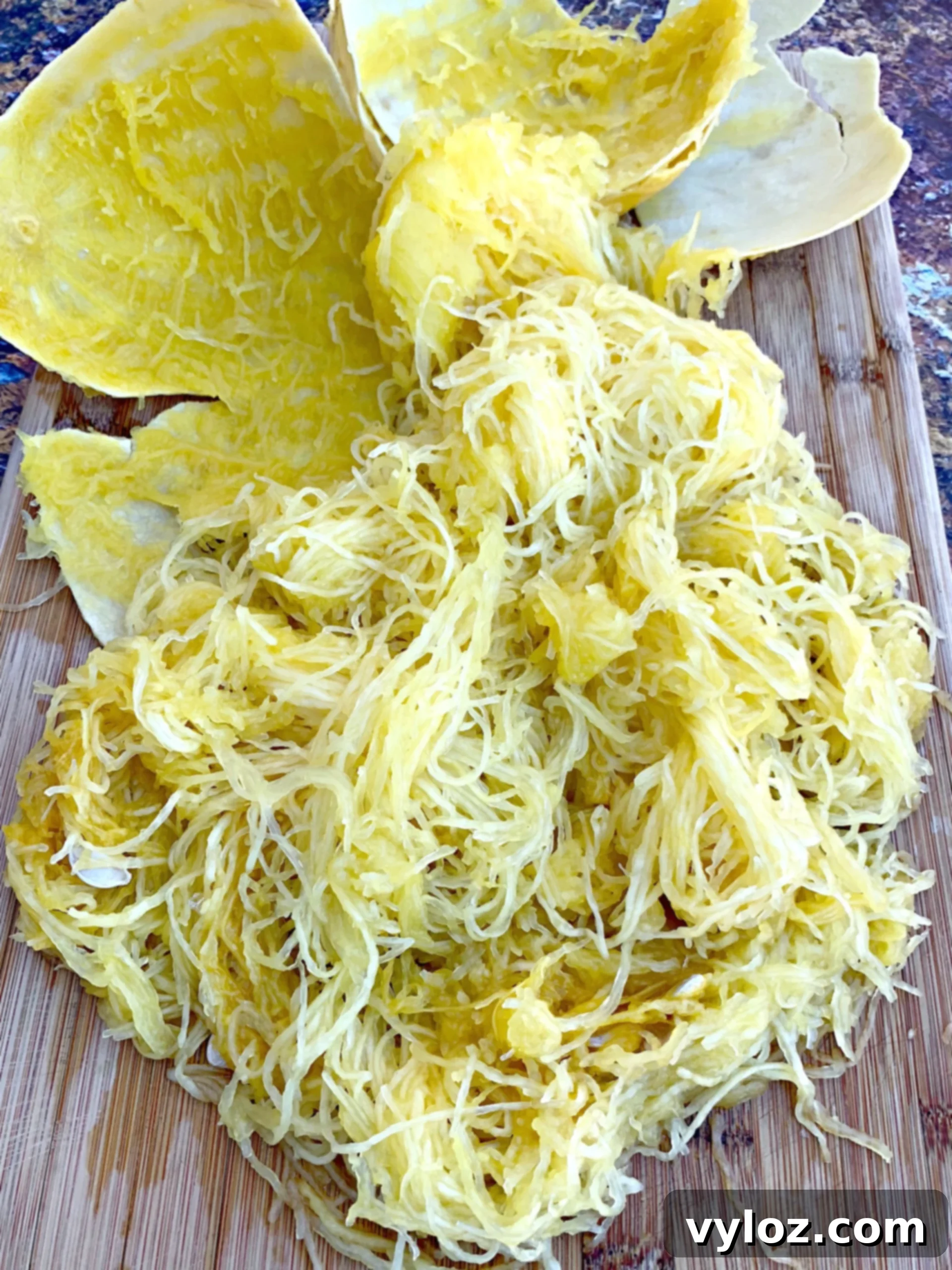 Perfectly separated spaghetti squash strands gracefully laid out on a clean wooden cutting board, meticulously prepared and ready to absorb delicious sauces.
