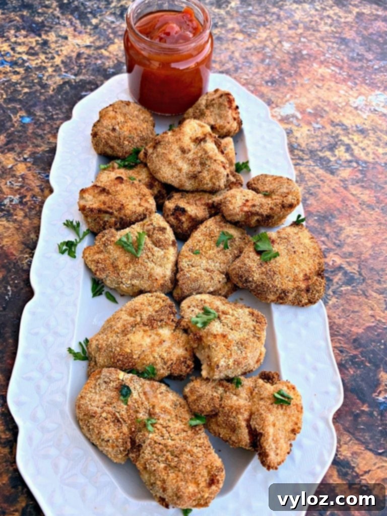 Crispy Air Fryer Chicken Nuggets 8 Air fryer chicken nuggets on a white plate with ketchup