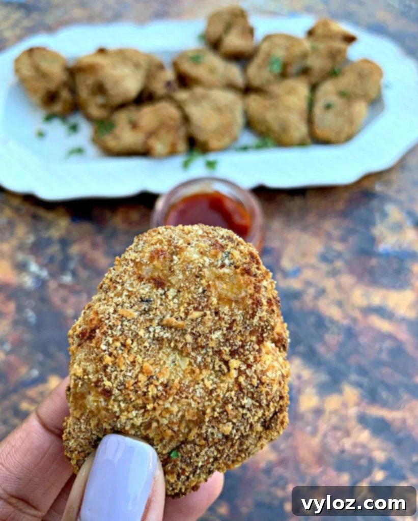 Crispy Air Fryer Chicken Nuggets 9 Person holding a single air fryer chicken nugget, showing its crispy texture