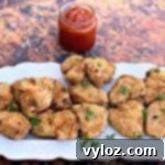 Crispy Air Fryer Chicken Nuggets 11 air fryer chicken nuggets on a white plate with ketchup
