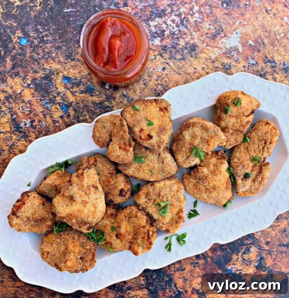 Crispy Air Fryer Chicken Nuggets 7 Air fryer chicken nuggets served on a white plate with ketchup for dipping