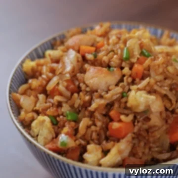 A bowl of hibachi chicken fried rice topped with green onions, served on a wooden table.