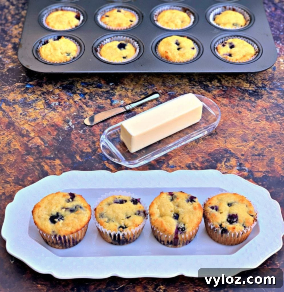 keto blueberry muffins on a white plate with a butter dish and a muffin tin with muffins