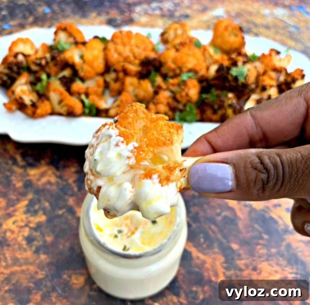 Crispy Air Fryer Buffalo Cauliflower 11 A person holding a serving of keto buffalo cauliflower wings with a side of ranch dip