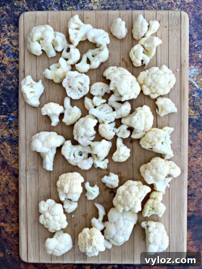 Crispy Air Fryer Buffalo Cauliflower 3 Fresh raw cauliflower florets on a wooden cutting board, ready for preparation