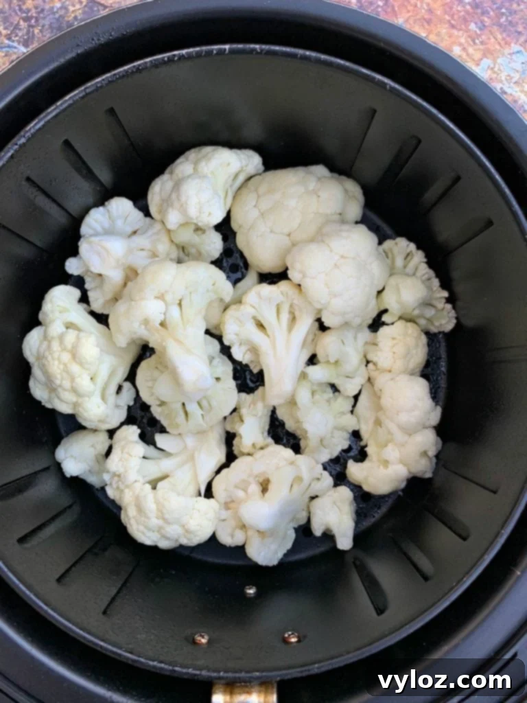 Crispy Air Fryer Buffalo Cauliflower 5 Raw cauliflower florets arranged in an air fryer basket before cooking