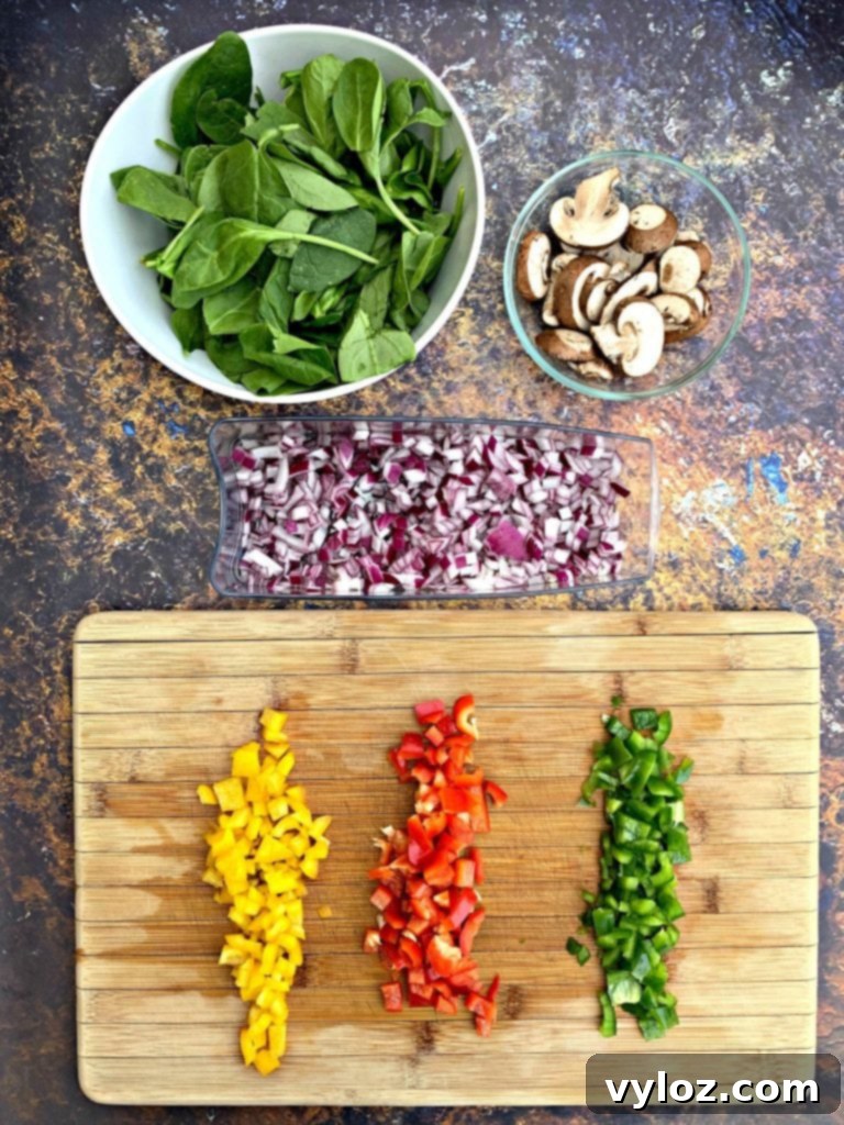 Keto Chorizo Egg and Cheese Breakfast Prep 4 chopped veggies on a cutting board with onions, spinach, and mushrooms in a bowl