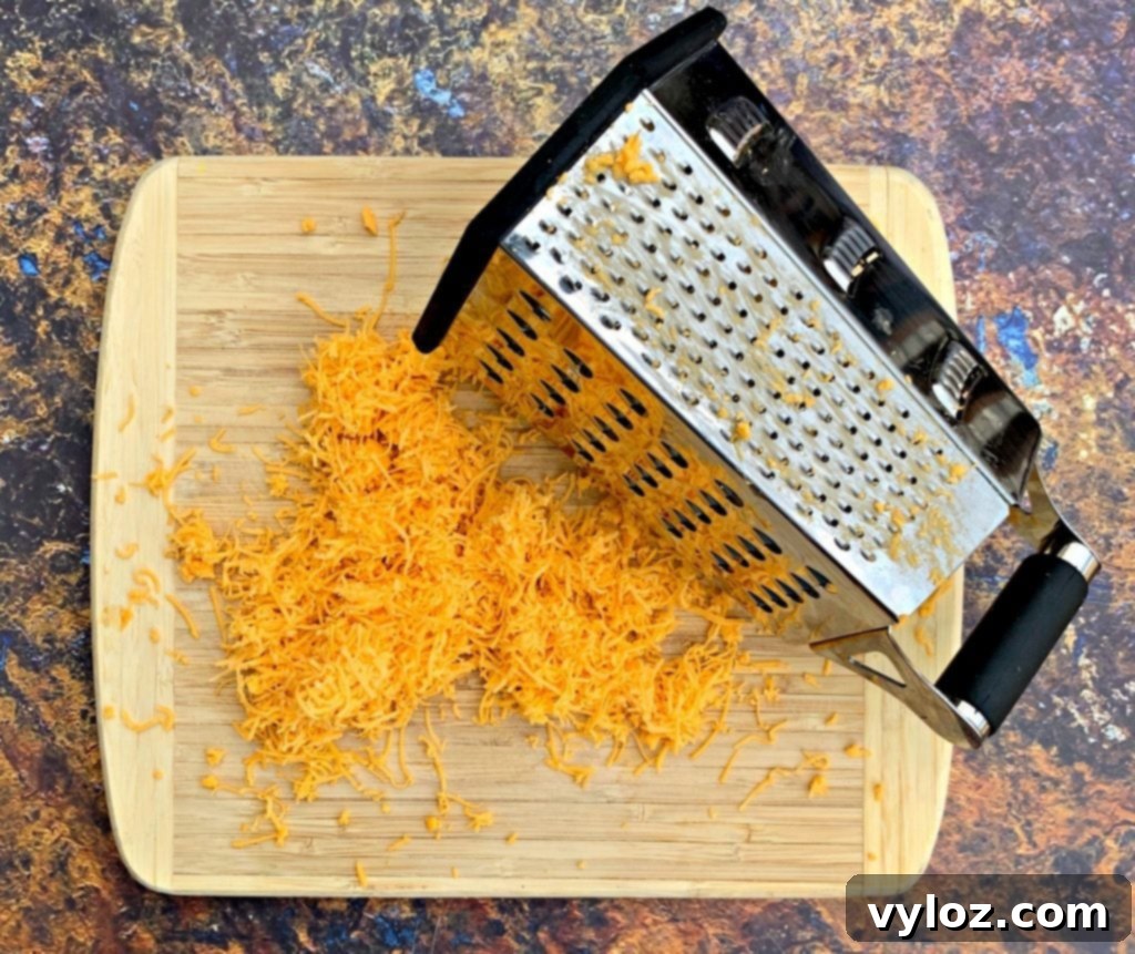 Keto Chorizo Egg and Cheese Breakfast Prep 6 shredded cheddar on a cutting board with a grater