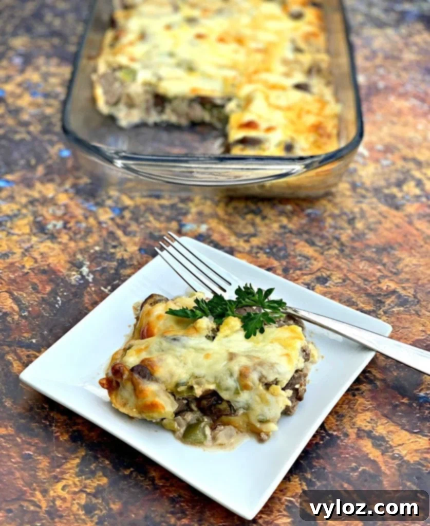 A single serving of Keto Low-Carb Philly Cheesesteak Casserole on a white plate, showcasing its rich, cheesy texture.