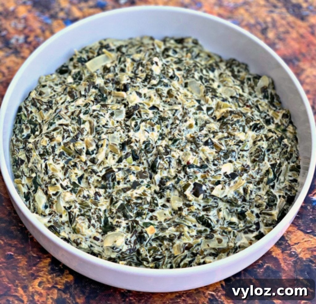 A serving of creamy, low-carb garlic creamed spinach in a white bowl, garnished and ready to eat.