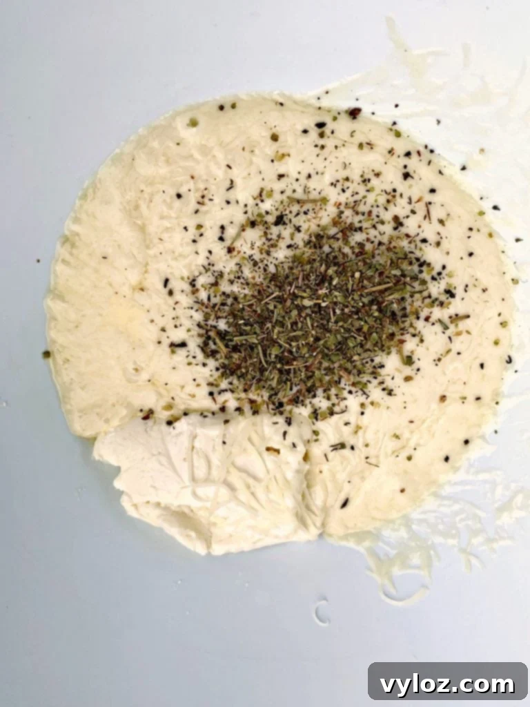 Keto pepperoni pizza dough in a ceramic bowl, seasoned with Italian herbs, indicating readiness for preparation.