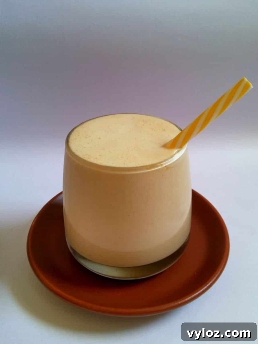 Peanut butter milkshake in a serving glass with straw