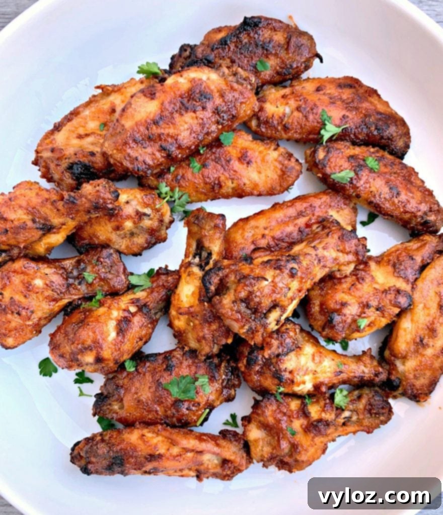 No-Fuss Sticky Honey BBQ Wings 7 A bowl filled with air fryer honey BBQ chicken wings, garnished with fresh herbs.