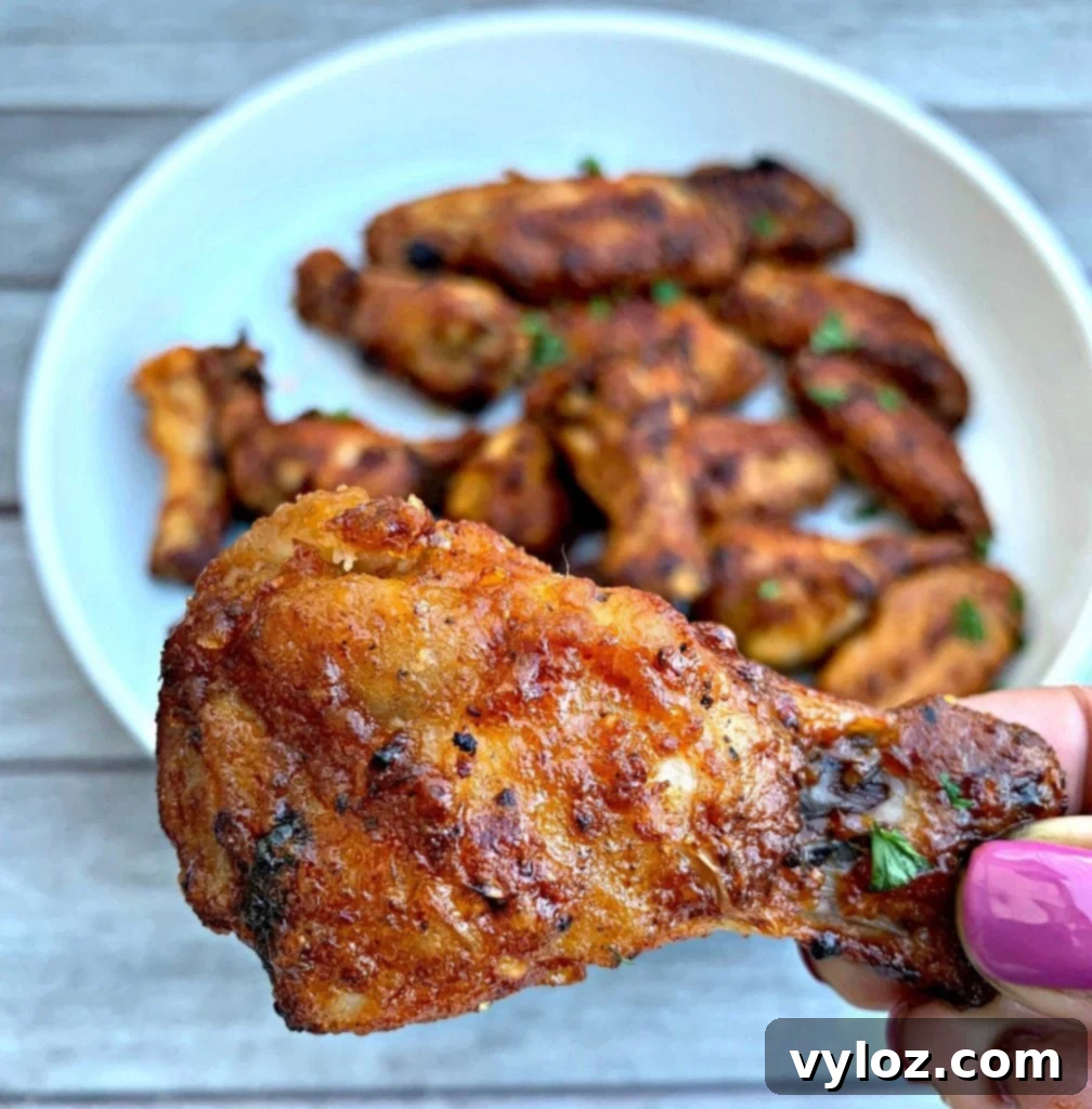 No-Fuss Sticky Honey BBQ Wings 9 A person holding an air fryer honey BBQ chicken wing, ready to eat.