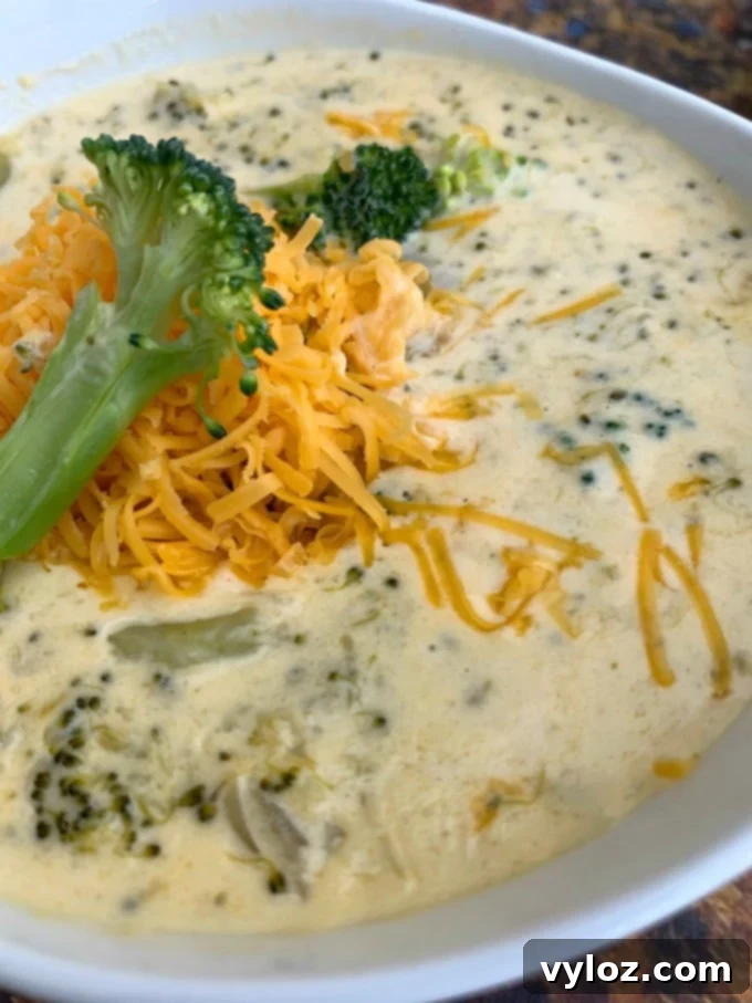 A large serving of keto low carb instant pot broccoli cheddar soup in a white bowl, highlighting its creamy texture.