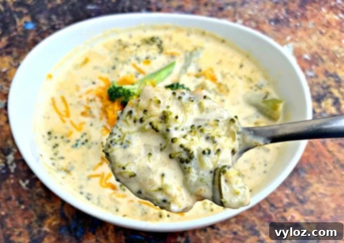 A spoon lifting a creamy bite of keto low carb instant pot broccoli cheddar soup, showing its texture.
