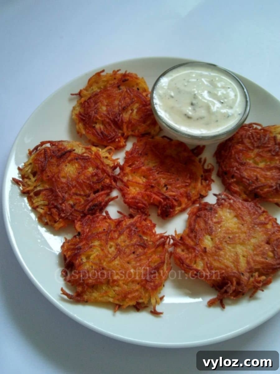 Crispy potato fritters served on a white plate with yogurt sauce.