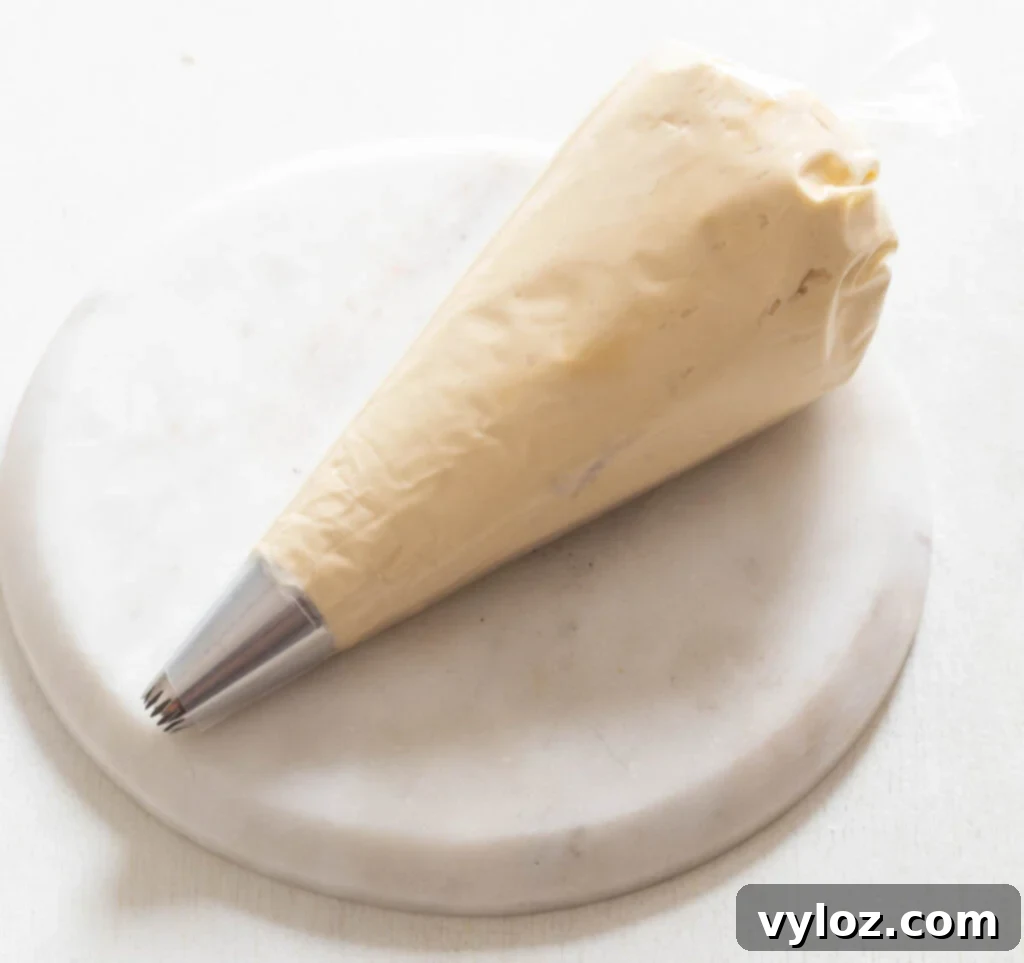 Creamy sugar-free buttercream frosting expertly loaded into a piping bag, with a decorative tip attached, prepared for elegant cupcake decoration.