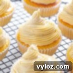 Person holding a delicious keto vanilla buttercream cupcake, showcasing its perfectly swirled frosting.