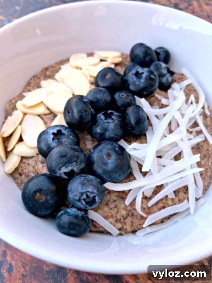 Keto hemp oatmeal with blueberries, almonds, and coconut in a white bowl, showing texture