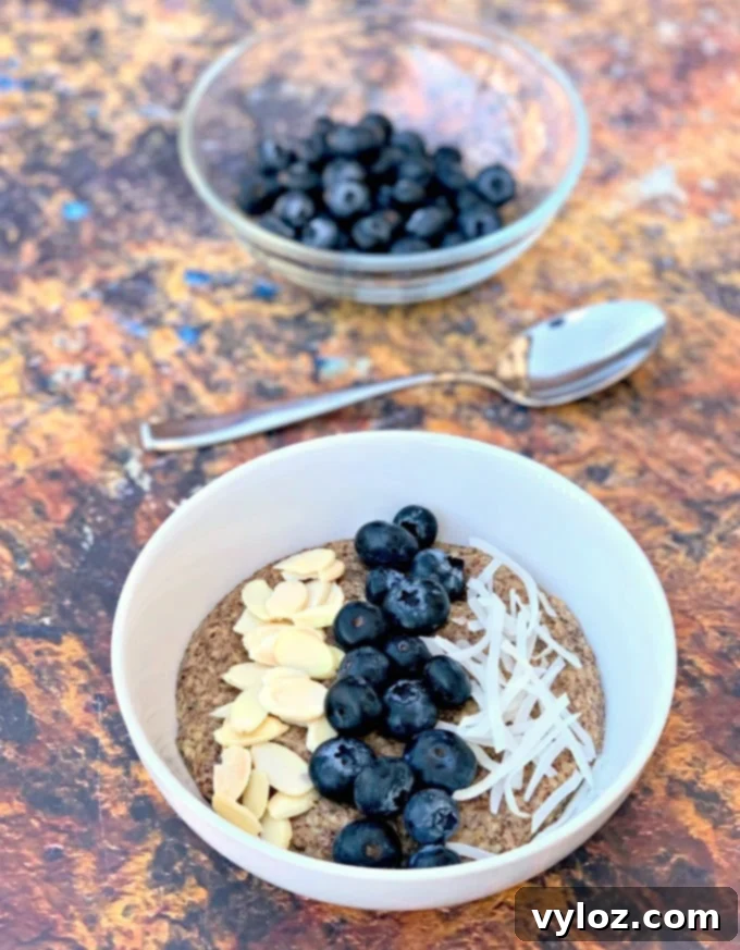 Keto hemp oatmeal with blueberries, almonds, and coconut in a white bowl, ready for toppings