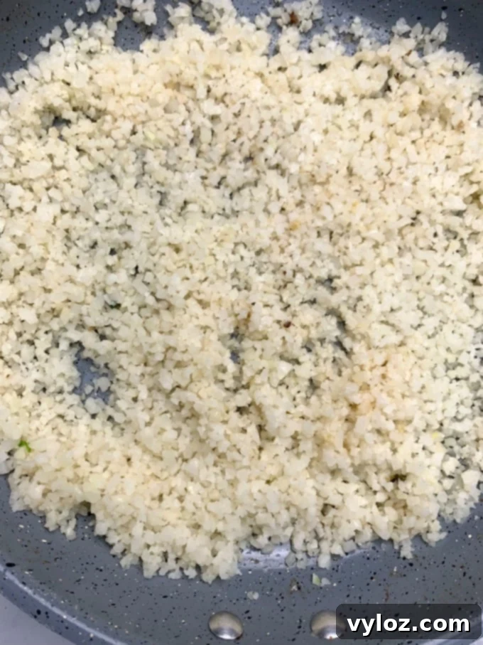 Cooked cauliflower rice in a skillet, ready to serve with beef and broccoli