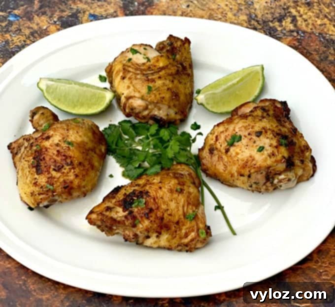 Crispy Air Fryer Cilantro Lime Chicken Thighs with fresh cilantro and lime wedges on a white plate