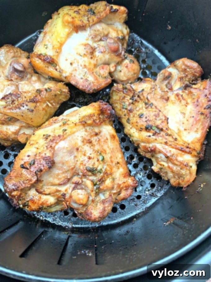 Air fryer keto low carb cilantro lime chicken thighs cooking in an air fryer basket, with golden-brown skin