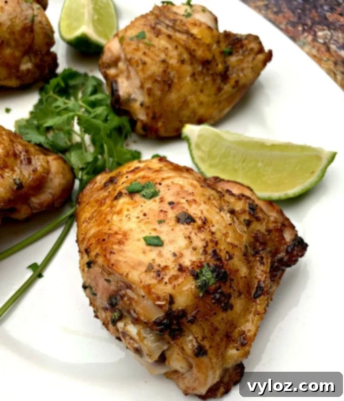 Perfectly cooked air fryer keto low carb cilantro lime chicken thighs served on a white plate with lime and fresh cilantro