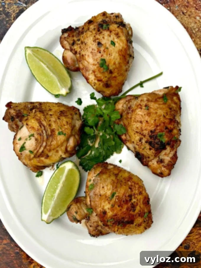Air fryer keto low carb cilantro lime chicken thighs on a white plate with lime and fresh cilantro