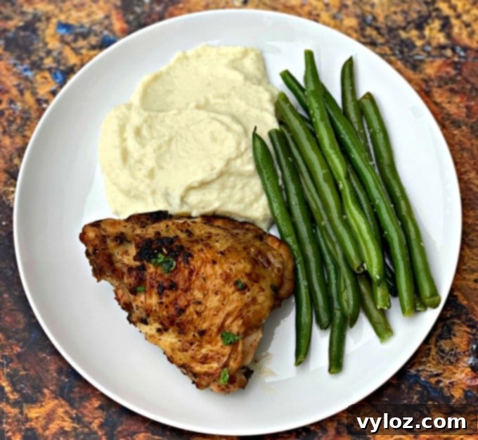 Keto low carb air fryer cilantro lime chicken thighs served with creamy cauliflower mash and crisp green beans on a white plate