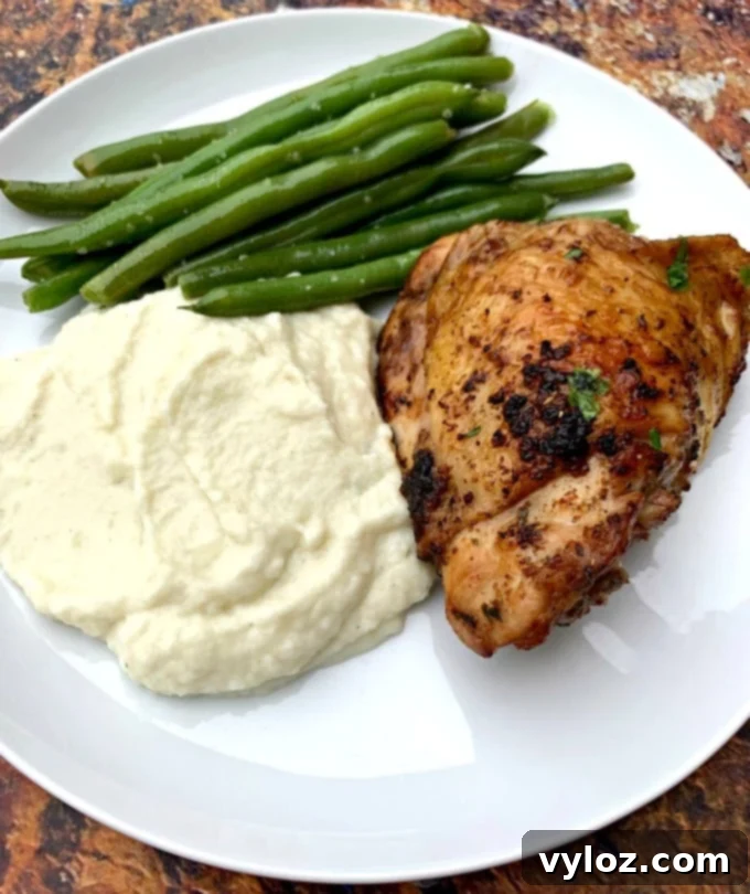 Keto low carb air fryer cilantro lime chicken thighs in a white plate with cauliflower mash and green beans, ready to serve