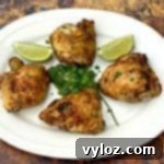 Air Fryer Cilantro Lime Chicken Thighs on a white plate with lime and fresh cilantro