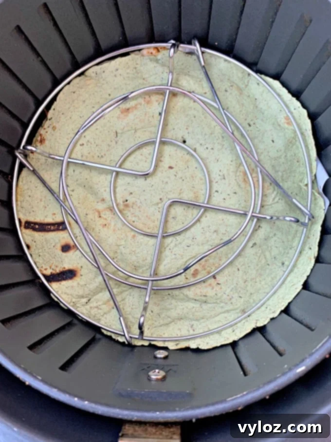 Another perspective of air fryer chicken quesadillas cooking, showcasing the even browning and melted cheese within the air fryer basket